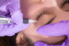 Το Cosmetologist προετοιμάζεται για την εφαρμογή της μόνιμης δερματοστιξίας eyeliner στο όμορφο νέο κορίτσι στο στούντιο ομορφιάς στοκ εικόνα με δικαίωμα ελεύθερης χρήσης Το Cosmetologist προετοιμάζεται για την εφαρμογή της μόνιμης δερματοστιξίας eyeliner στο όμορφο νέο κορίτσι στο στούντιο ομορφιάς στοκ εικόνα με δικαίωμα ελεύθερης χρήσης