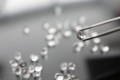 Το jeweler κρατά ένα διαμάντι στα τσιμπιδάκια στοκ εικόνα Το jeweler κρατά ένα διαμάντι στα τσιμπιδάκια στοκ εικόνα