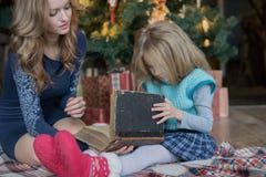 Το Mom και η κόρη ξοδεύουν τον ελεύθερο χρόνο διαβάζοντας ένα βιβλίο στο χριστουγεννιάτικο δέντρο στοκ φωτογραφία με δικαίωμα ελεύθερης χρήσης Το Mom και η κόρη ξοδεύουν τον ελεύθερο χρόνο διαβάζοντας ένα βιβλίο στο χριστουγεννιάτικο δέντρο στοκ φωτογραφία με δικαίωμα ελεύθερης χρήσης