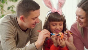 Το Mom και ο μπαμπάς βοηθούν την κόρη της να διακοσμήσει το αυγό Πάσχας με τις βούρτσες ευτυχής οικογένεια που προετοιμάζεται μαζ απόθεμα βίντεο Το Mom και ο μπαμπάς βοηθούν την κόρη της να διακοσμήσει το αυγό Πάσχας με τις βούρτσες ευτυχής οικογένεια που προετοιμάζεται μαζ απόθεμα βίντεο