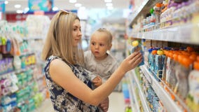 Το Mum μαζί με την κόρη ψάχνει τον πουρέ και τους χυμούς φρούτων παιδιών ` s απόθεμα βίντεο Το Mum μαζί με την κόρη ψάχνει τον πουρέ και τους χυμούς φρούτων παιδιών ` s απόθεμα βίντεο