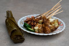 Το satay πιάτο τροφίμων οδών κοτόπουλου πλήρες με την καφετιά γλυκιά σάλτσα φυστικιών, τις φέτες κέικ ρυζιού και το φρέσκο αγγούρ στοκ εικόνα με δικαίωμα ελεύθερης χρήσης Το satay πιάτο τροφίμων οδών κοτόπουλου πλήρες με την καφετιά γλυκιά σάλτσα φυστικιών, τις φέτες κέικ ρυζιού και το φρέσκο αγγούρ στοκ εικόνα με δικαίωμα ελεύθερης χρήσης