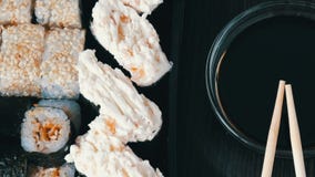 Το Stylishly έβαλε τα σούσια που τέθηκαν σε ένα μαύρο ξύλινο υπόβαθρο δίπλα στη σάλτσα σόγιας και τα κινεζικά ραβδιά μπαμπού σούσ φιλμ μικρού μήκους Το Stylishly έβαλε τα σούσια που τέθηκαν σε ένα μαύρο ξύλινο υπόβαθρο δίπλα στη σάλτσα σόγιας και τα κινεζικά ραβδιά μπαμπού σούσ φιλμ μικρού μήκους