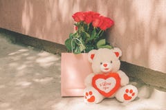 Το Teddy αντέχει και μια ανθοδέσμη των κόκκινων τριαντάφυλλων σε μια ρόδινη τσάντα στοκ φωτογραφία με δικαίωμα ελεύθερης χρήσης Το Teddy αντέχει και μια ανθοδέσμη των κόκκινων τριαντάφυλλων σε μια ρόδινη τσάντα στοκ φωτογραφία με δικαίωμα ελεύθερης χρήσης