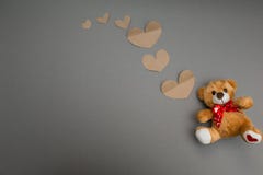 Το Teddy αφορά και πετώντας καρδιές εγγράφου ένα γκρίζο υπόβαθρο στοκ εικόνα Το Teddy αφορά και πετώντας καρδιές εγγράφου ένα γκρίζο υπόβαθρο στοκ εικόνα