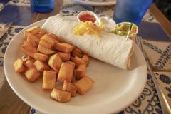 Το Yummy burrito προγευμάτων και οι κυβισμένες τηγανισμένες πατάτες σε ένα πιάτο σε ένα κεραμίδι παρουσιάζουν σε έναν resturant στοκ εικόνες με δικαίωμα ελεύθερης χρήσης Το Yummy burrito προγευμάτων και οι κυβισμένες τηγανισμένες πατάτες σε ένα πιάτο σε ένα κεραμίδι παρουσιάζουν σε έναν resturant στοκ εικόνες με δικαίωμα ελεύθερης χρήσης