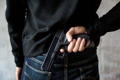 Το άτομο έκρυψε το πυροβόλο όπλο πίσω από την πλάτη τους στοκ φωτογραφία με δικαίωμα ελεύθερης χρήσης Το άτομο έκρυψε το πυροβόλο όπλο πίσω από την πλάτη τους στοκ φωτογραφία με δικαίωμα ελεύθερης χρήσης