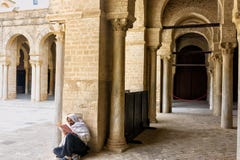Το άτομο διαβάζει το Quran στο προαύλιο του μεγάλου μουσουλμανικού τεμένους σε Kairouan, Τυνησία στοκ φωτογραφίες Το άτομο διαβάζει το Quran στο προαύλιο του μεγάλου μουσουλμανικού τεμένους σε Kairouan, Τυνησία στοκ φωτογραφίες