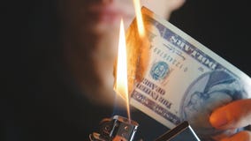 Το άτομο κινηματογραφήσεων σε πρώτο πλάνο καίει έναν λογαριασμό δολαρίων σε ένα σκοτεινό υπόβαθρο απόθεμα βίντεο Το άτομο κινηματογραφήσεων σε πρώτο πλάνο καίει έναν λογαριασμό δολαρίων σε ένα σκοτεινό υπόβαθρο απόθεμα βίντεο