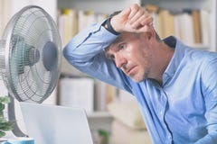 Το άτομο πάσχει από τη θερμότητα στο γραφείο ή στο σπίτι στοκ φωτογραφία με δικαίωμα ελεύθερης χρήσης Το άτομο πάσχει από τη θερμότητα στο γραφείο ή στο σπίτι στοκ φωτογραφία με δικαίωμα ελεύθερης χρήσης