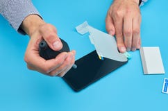 Το άτομο που αντικαθιστά το σπασμένο μετριασμένο προστάτη οθόνης γυαλιού για το smartphone στοκ φωτογραφίες με δικαίωμα ελεύθερης χρήσης Το άτομο που αντικαθιστά το σπασμένο μετριασμένο προστάτη οθόνης γυαλιού για το smartphone στοκ φωτογραφίες με δικαίωμα ελεύθερης χρήσης