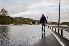 Το άτομο που περπατά στον πλημμυρισμένο δρόμο, νερό προέρχεται από τον ποταμό Tovdalselva σε Drangsholt σε Kristiansand, Νορβηγία στοκ εικόνες με δικαίωμα ελεύθερης χρήσης Το άτομο που περπατά στον πλημμυρισμένο δρόμο, νερό προέρχεται από τον ποταμό Tovdalselva σε Drangsholt σε Kristiansand, Νορβηγία στοκ εικόνες με δικαίωμα ελεύθερης χρήσης