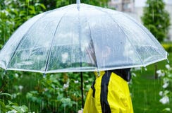 Το αγόρι στο κίτρινο αδιάβροχο κρατά τη διαφανή ομπρέλα κατά τη διάρκεια της βροχής Βροχερός καιρός στην άνοιξη στοκ φωτογραφία με δικαίωμα ελεύθερης χρήσης Το αγόρι στο κίτρινο αδιάβροχο κρατά τη διαφανή ομπρέλα κατά τη διάρκεια της βροχής Βροχερός καιρός στην άνοιξη στοκ φωτογραφία με δικαίωμα ελεύθερης χρήσης