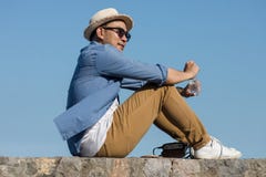 Το ασιατικό άτομο τουριστών ανοίγει ένα μπουκάλι νερό καθμένος ενάντια στοκ φωτογραφία με δικαίωμα ελεύθερης χρήσης Το ασιατικό άτομο τουριστών ανοίγει ένα μπουκάλι νερό καθμένος ενάντια στοκ φωτογραφία με δικαίωμα ελεύθερης χρήσης
