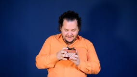 Το αστείο παχύ άτομο στο πορτοκαλί πουκάμισο ανοίγει ένα κιβώτιο με ένα δώρο φιλμ μικρού μήκους Το αστείο παχύ άτομο στο πορτοκαλί πουκάμισο ανοίγει ένα κιβώτιο με ένα δώρο φιλμ μικρού μήκους