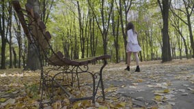 Το ελκυστικό κορίτσι εφήβων έντυσε στον κομψό ιματισμό που έχει έναν περίπατο στο πάρκο κοντά σε έναν πάγκο μια ημέρα φθινοπώρου απόθεμα βίντεο Το ελκυστικό κορίτσι εφήβων έντυσε στον κομψό ιματισμό που έχει έναν περίπατο στο πάρκο κοντά σε έναν πάγκο μια ημέρα φθινοπώρου απόθεμα βίντεο