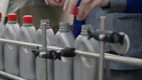 Το εργοστάσιο, χέρια των εργαζομένων κλείνει τα καπάκια στα γκρίζα πλαστικά μπουκάλια που κινούνται σε μια γραμμή μεταφορέων στο φιλμ μικρού μήκους Το εργοστάσιο, χέρια των εργαζομένων κλείνει τα καπάκια στα γκρίζα πλαστικά μπουκάλια που κινούνται σε μια γραμμή μεταφορέων στο φιλμ μικρού μήκους