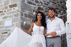 Το ευτυχές πορτρέτο ενός ζεύγους newlyweds θέτει να αγκαλιάσει μαζί κοντά στον παλαιό γκρίζο τοίχο στην Ελλάδα r στοκ εικόνες Το ευτυχές πορτρέτο ενός ζεύγους newlyweds θέτει να αγκαλιάσει μαζί κοντά στον παλαιό γκρίζο τοίχο στην Ελλάδα r στοκ εικόνες