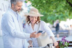 Το ευτυχές ώριμο ζεύγος που περπατά γύρω από την πόλη, γυναίκα ωθεί ένα ποδήλατο στοκ φωτογραφία Το ευτυχές ώριμο ζεύγος που περπατά γύρω από την πόλη, γυναίκα ωθεί ένα ποδήλατο στοκ φωτογραφία