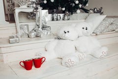 Το ζεύγος δύο άσπρου teddy αντέχει τα παιχνίδια καθμένος κοντά σε χριστουγεννιάτικο δέντρο και δύο κόκκινα φλιτζάνια του καφέ στοκ εικόνες Το ζεύγος δύο άσπρου teddy αντέχει τα παιχνίδια καθμένος κοντά σε χριστουγεννιάτικο δέντρο και δύο κόκκινα φλιτζάνια του καφέ στοκ εικόνες