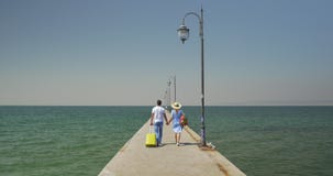 Το ζεύγος κερδίζει την κυλώντας τσάντα περπατώντας στην αποβάθρα απόθεμα βίντεο Το ζεύγος κερδίζει την κυλώντας τσάντα περπατώντας στην αποβάθρα απόθεμα βίντεο