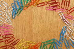Το ζωηρόχρωμο επίπεδο Paperclips βάζει στο ξύλινο ωοειδές κείμενο υποβάθρου στοκ εικόνες Το ζωηρόχρωμο επίπεδο Paperclips βάζει στο ξύλινο ωοειδές κείμενο υποβάθρου στοκ εικόνες