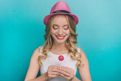 Το καλό νεαρό άτομο κρατά ένα μικρό ρόδινο lollipop στα χέρια της Εξετάζει το και χαμογελά κορίτσι ευτυχές στοκ φωτογραφία με δικαίωμα ελεύθερης χρήσης Το καλό νεαρό άτομο κρατά ένα μικρό ρόδινο lollipop στα χέρια της Εξετάζει το και χαμογελά κορίτσι ευτυχές στοκ φωτογραφία με δικαίωμα ελεύθερης χρήσης