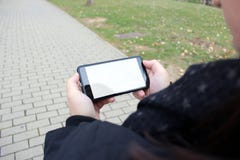 Το κορίτσι εξετάζει το smartphone της περπατώντας μέσω του πάρκου στοκ εικόνες Το κορίτσι εξετάζει το smartphone της περπατώντας μέσω του πάρκου στοκ εικόνες