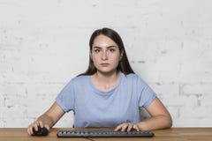 Το κορίτσι φαίνεται ευθεία εκμετάλλευση το ποντίκι στο χέρι της και δακτυλογράφηση στο πληκτρολόγιο στοκ εικόνα με δικαίωμα ελεύθερης χρήσης Το κορίτσι φαίνεται ευθεία εκμετάλλευση το ποντίκι στο χέρι της και δακτυλογράφηση στο πληκτρολόγιο στοκ εικόνα με δικαίωμα ελεύθερης χρήσης
