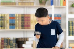 Το νέες ασιατικές χαμόγελο αγοριών και η ενίσχυση λαβής - γυαλί η βιβλιοθήκη είναι στοκ φωτογραφίες Το νέες ασιατικές χαμόγελο αγοριών και η ενίσχυση λαβής - γυαλί η βιβλιοθήκη είναι στοκ φωτογραφίες