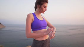 Το νέο όμορφο κορίτσι sportswear αγγίζει ένα έξυπνο ρολόι στο ηλιοβασίλεμα από τον ωκεανό Προωθήστε ένα workout app φιλμ μικρού μήκους Το νέο όμορφο κορίτσι sportswear αγγίζει ένα έξυπνο ρολόι στο ηλιοβασίλεμα από τον ωκεανό Προωθήστε ένα workout app φιλμ μικρού μήκους
