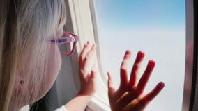 Το ξανθό κορίτσι στα ρόδινα γυαλιά εξετάζει το παράθυρο αεροπλάνων στα σύννεφα φιλμ μικρού μήκους Το ξανθό κορίτσι στα ρόδινα γυαλιά εξετάζει το παράθυρο αεροπλάνων στα σύννεφα φιλμ μικρού μήκους