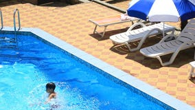 Το παιδί κολυμπά στο μπλε νερό της λίμνης επάνω από την όψη φιλμ μικρού μήκους Το παιδί κολυμπά στο μπλε νερό της λίμνης επάνω από την όψη φιλμ μικρού μήκους