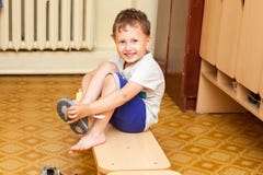 Το παιδί βάζει στα παπούτσια στον παιδικό σταθμό στοκ εικόνες Το παιδί βάζει στα παπούτσια στον παιδικό σταθμό στοκ εικόνες