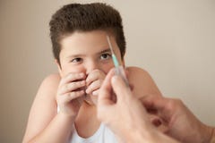 Το παχύ μικρό παιδί κάλυψε το πρόσωπό του μακρυά από την έγχυση στοκ εικόνες Το παχύ μικρό παιδί κάλυψε το πρόσωπό του μακρυά από την έγχυση στοκ εικόνες
