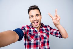 Το πολύ συγκινημένο νέο hipster στην περιστασιακή ένδυση κάνει selfie τον πυροβολισμό στοκ φωτογραφία με δικαίωμα ελεύθερης χρήσης Το πολύ συγκινημένο νέο hipster στην περιστασιακή ένδυση κάνει selfie τον πυροβολισμό στοκ φωτογραφία με δικαίωμα ελεύθερης χρήσης