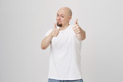 Το πορτρέτο στούντιο του θετικού διέγειρε το φαλακρό γενειοφόρο αρσενικό που παρουσιάζει αντίχειρες στη κάμερα και που χαμογελά χ στοκ φωτογραφία Το πορτρέτο στούντιο του θετικού διέγειρε το φαλακρό γενειοφόρο αρσενικό που παρουσιάζει αντίχειρες στη κάμερα και που χαμογελά χ στοκ φωτογραφία