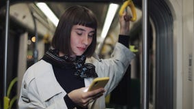Το πορτρέτο της νέας γυναίκας hipster κρατά το κιγκλίδωμα, χρησιμοποιώντας το smartphone στεμένος δημόσια τη μεταφορά city lights απόθεμα βίντεο Το πορτρέτο της νέας γυναίκας hipster κρατά το κιγκλίδωμα, χρησιμοποιώντας το smartphone στεμένος δημόσια τη μεταφορά city lights απόθεμα βίντεο