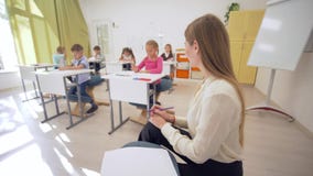 Το πορτρέτο της χαμογελώντας θηλυκής γυναίκας δασκάλων κατά τη διάρκεια του μαθήματος εκπαίδευσης με τους μαθητές στην τάξη στο δ απόθεμα βίντεο Το πορτρέτο της χαμογελώντας θηλυκής γυναίκας δασκάλων κατά τη διάρκεια του μαθήματος εκπαίδευσης με τους μαθητές στην τάξη στο δ απόθεμα βίντεο