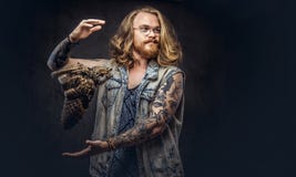 Το πορτρέτο του α το redhead αρσενικό hipster με τη μακριά άφθονη τρίχα και η πλήρης γενειάδα έντυσε σε μια μπλούζα και το σακάκι στοκ εικόνες Το πορτρέτο του α το redhead αρσενικό hipster με τη μακριά άφθονη τρίχα και η πλήρης γενειάδα έντυσε σε μια μπλούζα και το σακάκι στοκ εικόνες