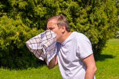 Το πορτρέτο των ατόμων που φτερνίζονται από την αλλεργία, σε μια άσπρη μπλούζα, στέκεται στο πάρκο στοκ φωτογραφίες με δικαίωμα ελεύθερης χρήσης Το πορτρέτο των ατόμων που φτερνίζονται από την αλλεργία, σε μια άσπρη μπλούζα, στέκεται στο πάρκο στοκ φωτογραφίες με δικαίωμα ελεύθερης χρήσης