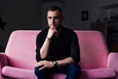 Το πρότυπο ατόμων κάθεται στο ρόδινο καναπέ στο εσωτερικό σοφιτών Επιχειρηματίας σε ένα μαύρα πουκάμισο και ένα ρολόι, μπλε εσώρο στοκ φωτογραφίες με δικαίωμα ελεύθερης χρήσης Το πρότυπο ατόμων κάθεται στο ρόδινο καναπέ στο εσωτερικό σοφιτών Επιχειρηματίας σε ένα μαύρα πουκάμισο και ένα ρολόι, μπλε εσώρο στοκ φωτογραφίες με δικαίωμα ελεύθερης χρήσης