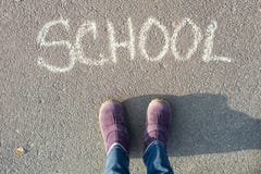 Το σχολείο λέξης στην άσφαλτο και τα πόδια του σπουδαστή στοκ φωτογραφία με δικαίωμα ελεύθερης χρήσης Το σχολείο λέξης στην άσφαλτο και τα πόδια του σπουδαστή στοκ φωτογραφία με δικαίωμα ελεύθερης χρήσης