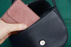 Το χέρι βγάζει ένα καφετί πορτοφόλι από μια ανοικτή μαύρη τσάντα δέρματος στοκ εικόνα Το χέρι βγάζει ένα καφετί πορτοφόλι από μια ανοικτή μαύρη τσάντα δέρματος στοκ εικόνα