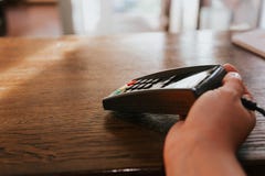 Το χέρι με το τερματικό και την πιστωτική κάρτα του πελάτη o στοκ φωτογραφία με δικαίωμα ελεύθερης χρήσης Το χέρι με το τερματικό και την πιστωτική κάρτα του πελάτη o στοκ φωτογραφία με δικαίωμα ελεύθερης χρήσης