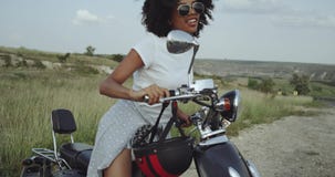 Το χαριτωμένο κορίτσι με την τρίχα Afro προσπαθεί να οδηγήσει μια μοτοσικλέτα ισχίων, που έχει έναν χρόνο διασκέδασης φιλμ μικρού μήκους Το χαριτωμένο κορίτσι με την τρίχα Afro προσπαθεί να οδηγήσει μια μοτοσικλέτα ισχίων, που έχει έναν χρόνο διασκέδασης φιλμ μικρού μήκους