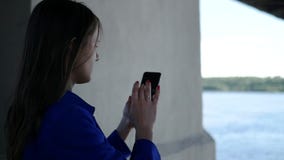 Το όμορφο λεπτό κορίτσι στέκεται κοντά στην πηγή με ένα τηλέφωνο στο χέρι της, γράφει ένα μήνυμα, το τηλέφωνο απεικονίζει τις ακτ φιλμ μικρού μήκους Το όμορφο λεπτό κορίτσι στέκεται κοντά στην πηγή με ένα τηλέφωνο στο χέρι της, γράφει ένα μήνυμα, το τηλέφωνο απεικονίζει τις ακτ φιλμ μικρού μήκους