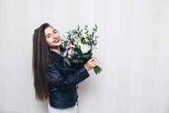 Το όμορφο μοντέρνο κορίτσι έντυσε στο σακάκι δέρματος, που κρατά την ανθοδέσμη των λουλουδιών και που θέτει ενάντια στον άσπρο το στοκ φωτογραφία με δικαίωμα ελεύθερης χρήσης Το όμορφο μοντέρνο κορίτσι έντυσε στο σακάκι δέρματος, που κρατά την ανθοδέσμη των λουλουδιών και που θέτει ενάντια στον άσπρο το στοκ φωτογραφία με δικαίωμα ελεύθερης χρήσης