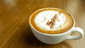 Τοπ άποψη ενός φλυτζανιού του καυτού καφέ cappuccino με την κρέμα, αφρός γάλακτος στον ξύλινο πίνακα για το πρωί φρεσκάδας ή μετά στοκ φωτογραφία με δικαίωμα ελεύθερης χρήσης Τοπ άποψη ενός φλυτζανιού του καυτού καφέ cappuccino με την κρέμα, αφρός γάλακτος στον ξύλινο πίνακα για το πρωί φρεσκάδας ή μετά στοκ φωτογραφία με δικαίωμα ελεύθερης χρήσης