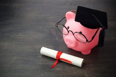 Τράπεζα Piggy με ένα grad ΚΑΠ και δίπλωμα στον ξύλινο πίνακα, υποτροφία εκπαίδευσης στοκ εικόνα Τράπεζα Piggy με ένα grad ΚΑΠ και δίπλωμα στον ξύλινο πίνακα, υποτροφία εκπαίδευσης στοκ εικόνα